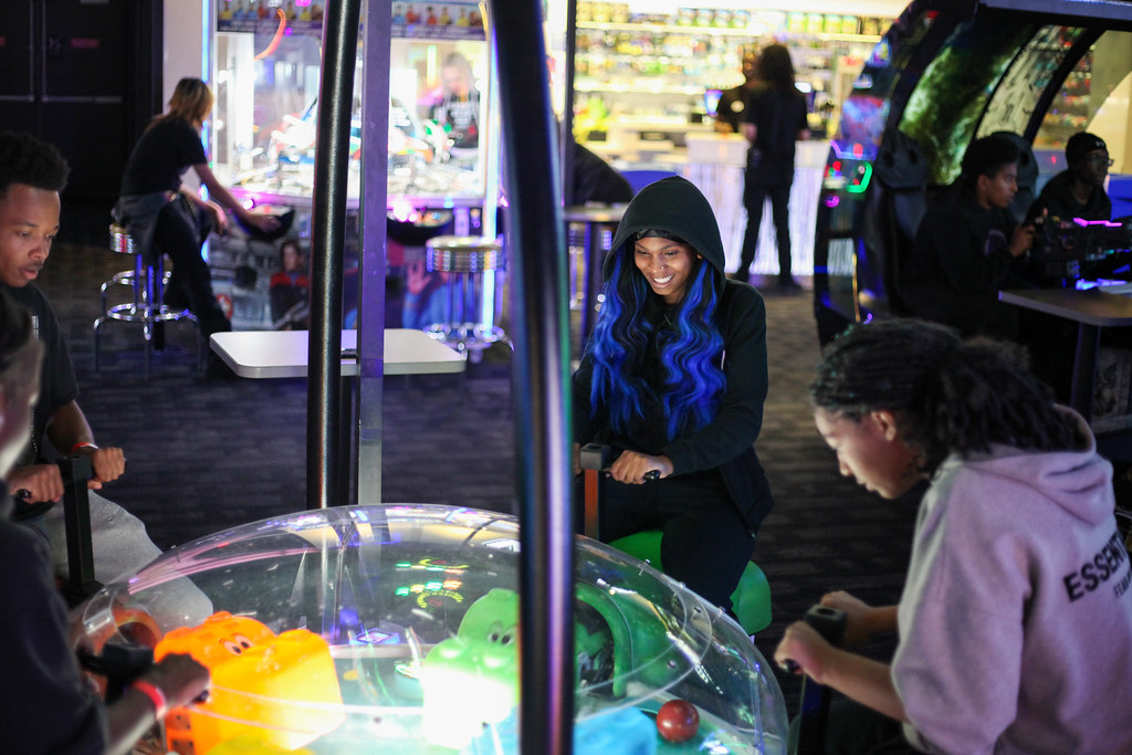 Students laughing together while playing an arcade game